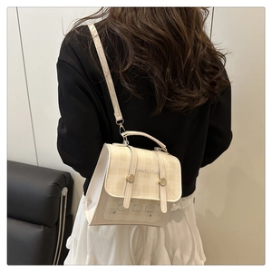 Detail of checkered cream mini bag with cute bear pattern and gold hardware on model