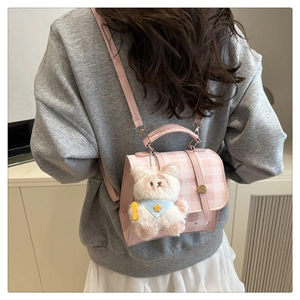 Rear view of model wearing pink checkered mini backpack with teddy bear charm