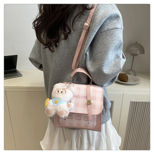 Pink and white checkered mini bag with teddy bear charm shown in a lifestyle setting