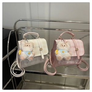 Detail view of plaid mini backpacks in cream and pink featuring cute plush bear charms