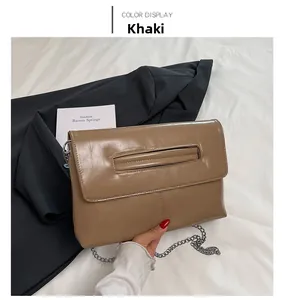 Détail du sac enveloppe en cuir kaki avec bandoulière en chaîne argentée et poignée