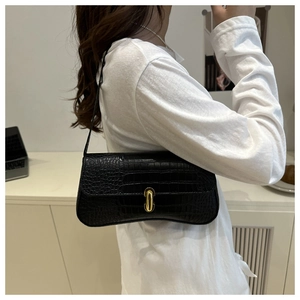 Détail du similicuir à motif crocodile noir sur un sac porté épaule avec boucle dorée