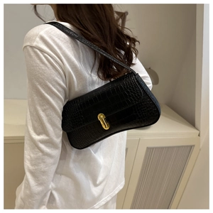 Détail du sac sous l'aisselle noir motif crocodile avec fermoir doré sur modèle
