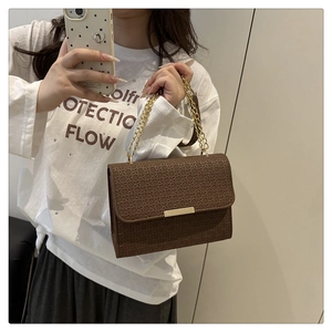 Détail du sac à bandoulière marron avec chaîne dorée et gaufrage géométrique chic