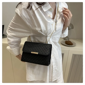 Détail du sac bandoulière noir tissé avec chaîne dorée et boucle métallique