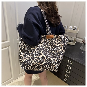 Detail of leopard print canvas tote bag with front pocket and leather logo patch
