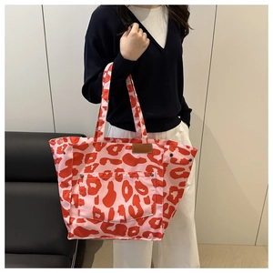 Detailed close-up of a pink leopard print canvas tote bag with front pocket and metal studs