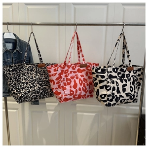 Detail view of large canvas tote bags with leopard and cow print patterns and metal rivets
