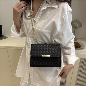 Sac bandoulière noir matelassé avec chaîne dorée et fermoir en métal porté par un mannequin