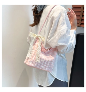 Detail of pink gingham canvas tote bag with daisy prints and a white lace bow detail