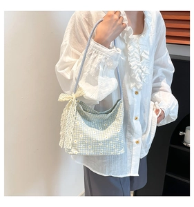 Detail of floral daisy pattern canvas bag with large cream lace bow shown on model