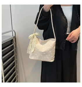 Detail of checkered shoulder bag featuring daisy embroidery and delicate lace bow accent