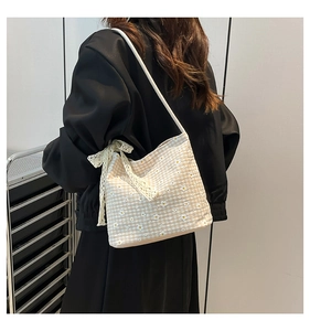 Detail of canvas bucket bag featuring daisy embroidery and a white lace bow accessory