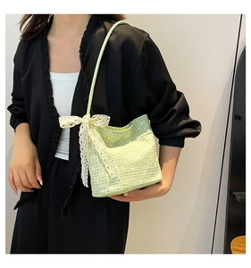 Close-up of light green plaid canvas bag featuring white floral print and a lace bow