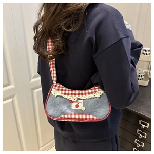 Detail of vintage denim and red plaid underarm bag with delicate lace trim and button accents