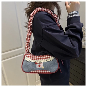 Détail du sac à épaule en denim bleu avec bandoulière plissée à carreaux rouges