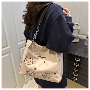 Detail of beige nylon tote bag featuring cartoon cat print and brown leather chain strap