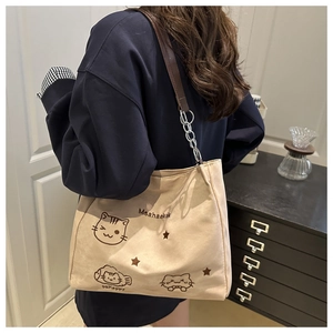 Detail of canvas tote bag featuring cat graphic with leather and chain shoulder strap