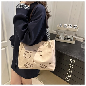 Detail of beige canvas tote with embroidered cartoon cats and silver chain strap