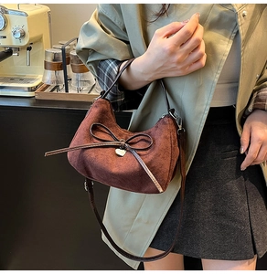 Detail of vintage brown suede bag with leather bow and golden heart charm decoration