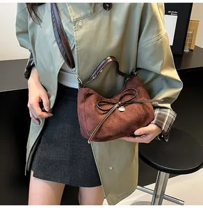 Detail of vintage brown suede crescent bag featuring a leather bow and heart charm