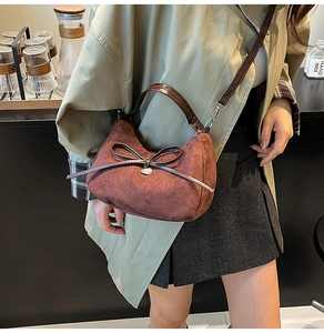 Detail of dark brown matte suede handbag with a leather bow on a shoulder strap