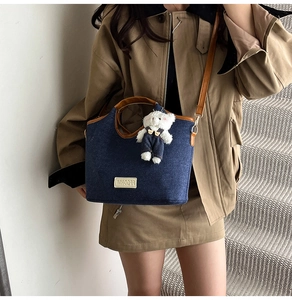 Détail du sac cabas en denim bleu foncé avec bordure en cuir et breloque ours incluse