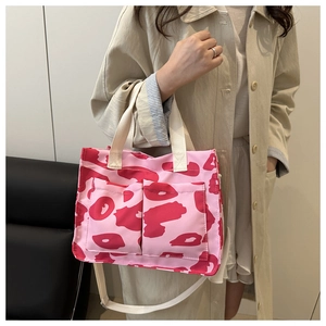 Dettaglio della borsa tote in tela rosa a motivi con tasche anteriori e tracolla
