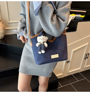 Vue détaillée du sac seau en jean bleu avec bandoulière en cuir et pendentif ours
