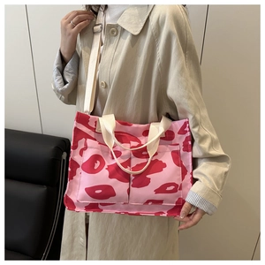 Dettaglio della borsa tote in tela rosa con tasche anteriori e tracolla regolabile
