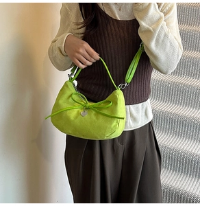 Detail of lime green suede dumpling bag with elegant bow knot and silver heart pendant