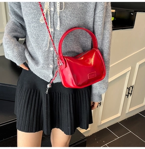 Détail du sac bandoulière rouge brillant avec bandoulière chaîne sur une tenue chic