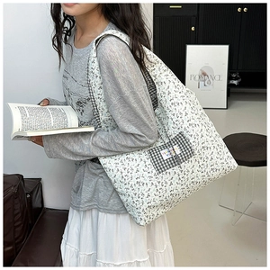Detailed close-up of large floral canvas tote bag with black and white plaid pocket detail
