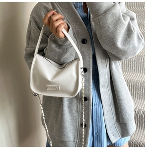 Detalle del bolso de media luna blanco crema con logo Fashion y correa de cadena