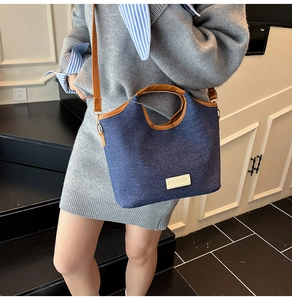 Detail der dunkelblauen Denim-Beuteltasche mit braunem Lederbesatz und Trageriemen