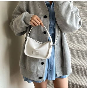 Détail du sac à main en cuir blanc avec plaque en métal et bandoulière chaîne