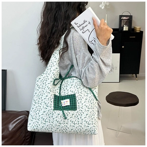 Detailed view of floral canvas tote bag with green plaid pocket and ribbon bow detail