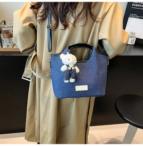 Sac seau en denim bleu avec patch en cuir et breloque ours en peluche sur modèle
