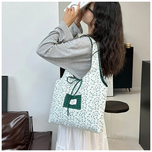 Close-up of floral tote bag with green checkered pocket and drawstring decoration