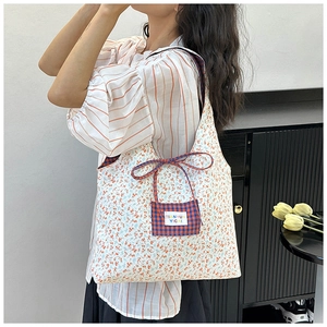 Detail einer floralen Canvas-Tasche mit orangefarbenen Blumen und rot karierter Tasche