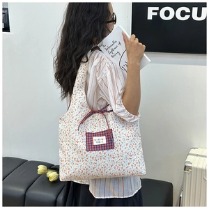 Floral canvas tote bag featuring an orange plaid pocket and white label detail
