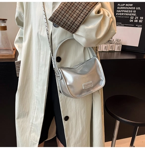 Détail du sac bandoulière argenté brillant avec chaîne et logo Fashion gravé