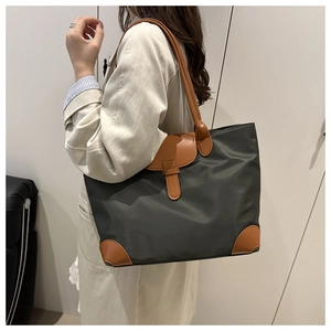Detail of nylon tote bag with leather handles and reinforced base corners