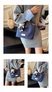 Detail der blauen Denim-Beuteltasche mit braunem Lederbesatz und süßem Teddybär-Anhänger