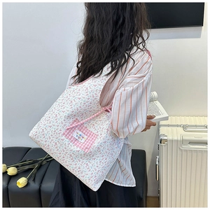 Floral canvas tote bag featuring a pink plaid pocket and colorful brand label details