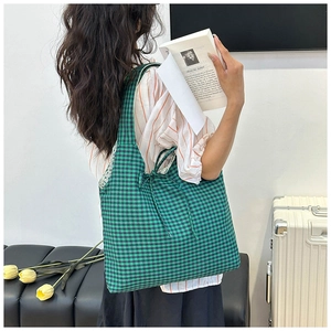 Detail view of canvas tote bag with green checkered pattern and bow tie decoration