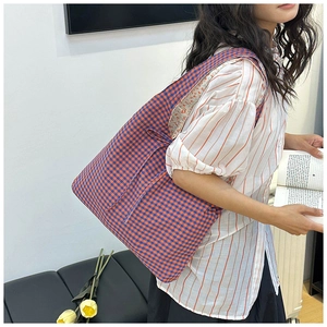 Detail view of large canvas shoulder bag with blue checkered pattern and floral lining