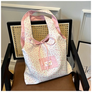 Detailed view of floral canvas tote bag with pink flower pattern and gingham pocket bow
