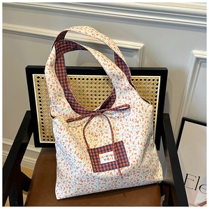 Close-up of floral tote bag with blue orange plaid lining and decorative bow detail