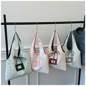 Detailansicht von vier floralen Baumwoll-Tote-Bags mit Karotaschen und Schleifen